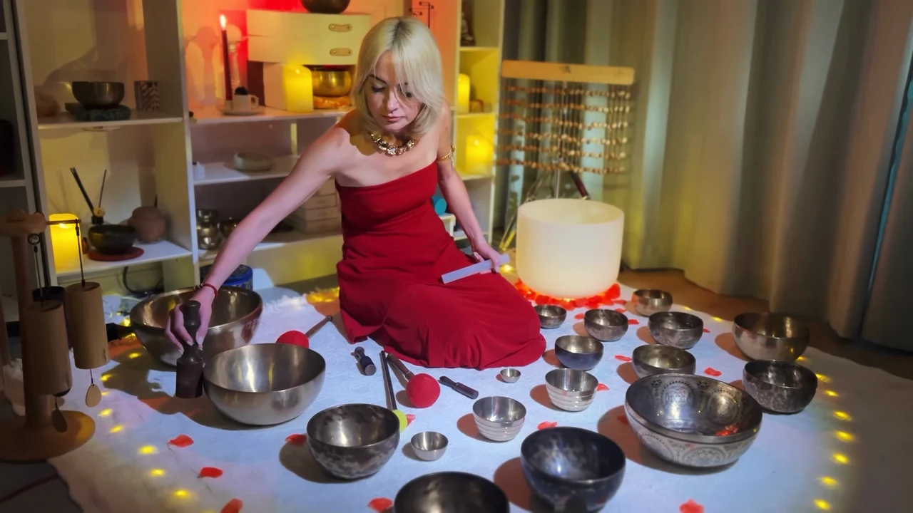 Viktoria in a red dress surrounded by Tibetan bowls, with a white crystal bowl behind her.