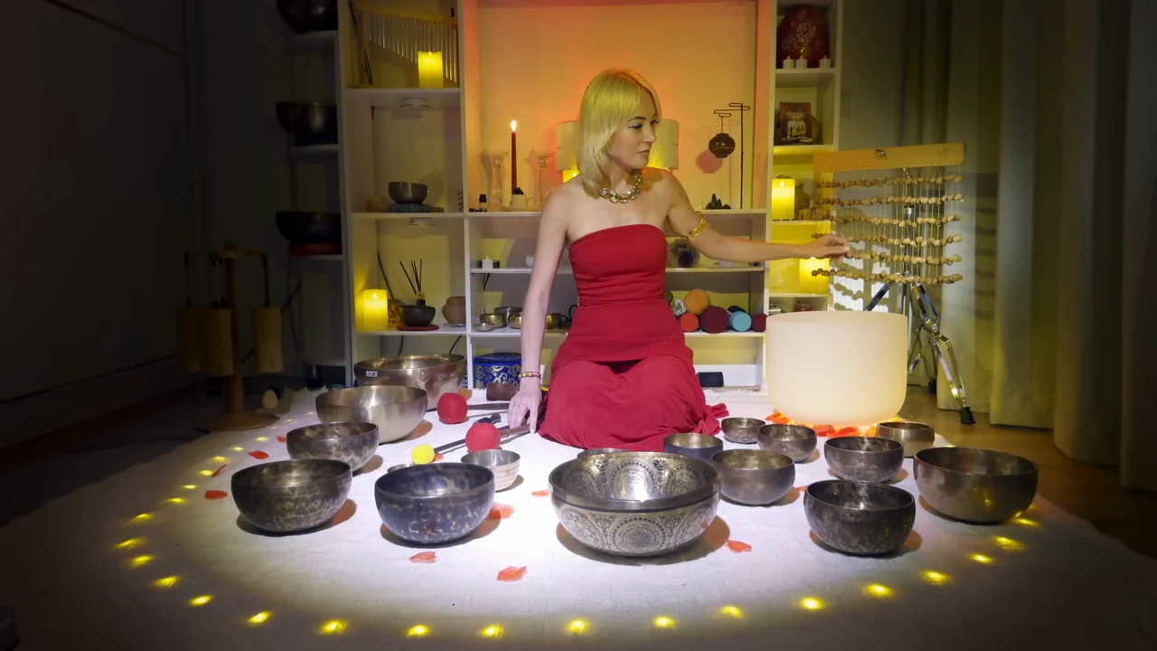 Viktoria in a red dress surrounded by Tibetan bowls, with a white crystal bowl behind her.