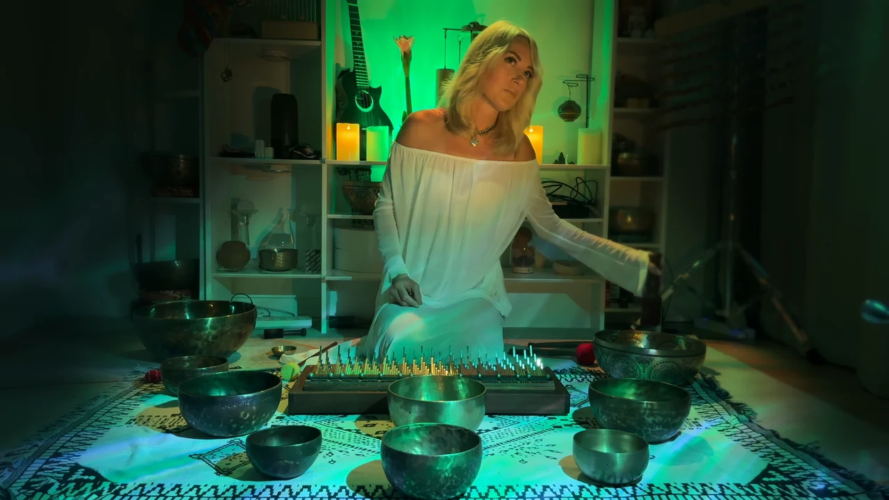 Viktoria in a white dress playing Tibetan singing bowls, with a kalimba in front of her.