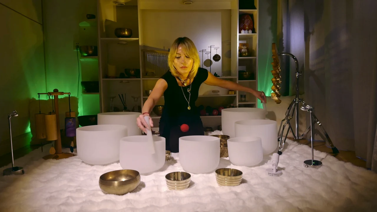Viktoria with crystal and Tibetan singing bowls in a softly lit recording space.